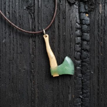 Embrace the raw beauty of nature with this handcrafted axe pendant. Meticulously carved from deep green nephrite and ancient pet…