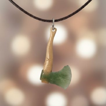Exquisitely handcrafted, this unique axe pendant pairs deep green nephrite with the organic texture of petrified wood. A timeles…