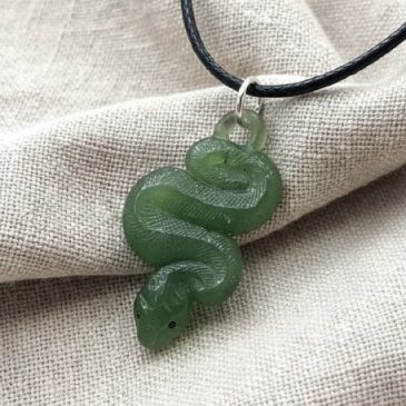 Nephrite jade snake pendant. Features striking red garnet eyes, symbolizing passion and strength. Elegant and powerful accessory…