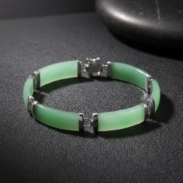 This elegant handcrafted bracelet features a stunning interplay of natural green jade and polished sterling silver. A timeless a…