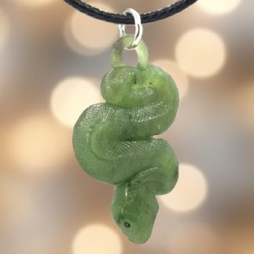 This exquisite nephrite jade pendant features a meticulously carved snake, accented by vibrant red garnet eyes. The deep green s…