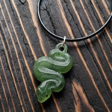 Adorn yourself with this exquisite Nephrite Snake Pendant. Carved from deep green jade with striking red garnet eyes, it balance…