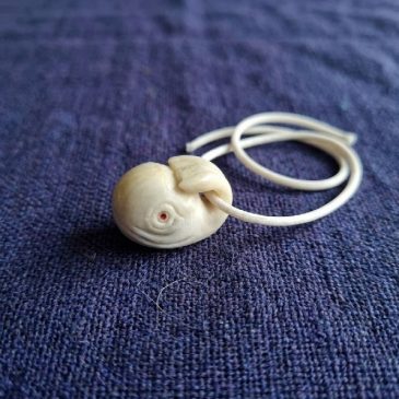Elegant White Jade Moby Dick pendant with faceted gemstone eyes. A unique piece of artisan jewelry.