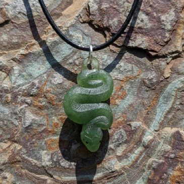 This elegant Nephrite Snake Pendant features expertly carved green jade, showcasing fluid curves and a polished finish. Its stri…