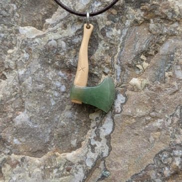 This handcrafted axe pendant features a striking blend of deep green nephrite and ancient petrified wood, merging natural textur…