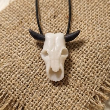 Handcrafted white jade bull skull pendant with obsidian horns. A bold, minimalist statement piece for a unique look….