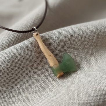 Handcrafted from nephrite and petrified wood, this axe pendant blends deep forest greens with ancient textures. A unique piece o…