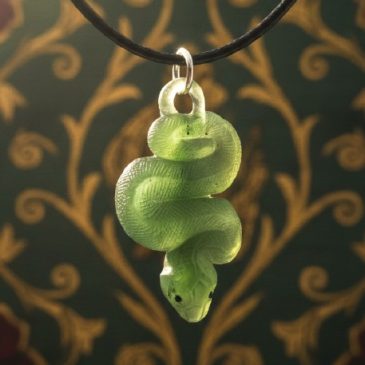 Adorn your style with this exquisite Nephrite Snake Pendant. Expertly carved from deep green jade, it features vibrant red garne…