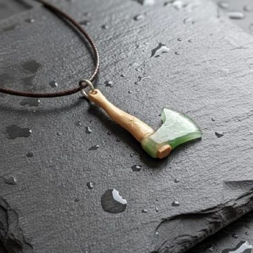 This handcrafted Axe Pendant features a striking combination of dark green nephrite and ancient petrified wood. Its minimalist d…